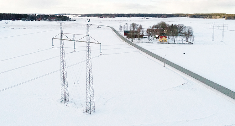 En bild som är tagen från luften. Den visar ett fält med en stor ledning för el.