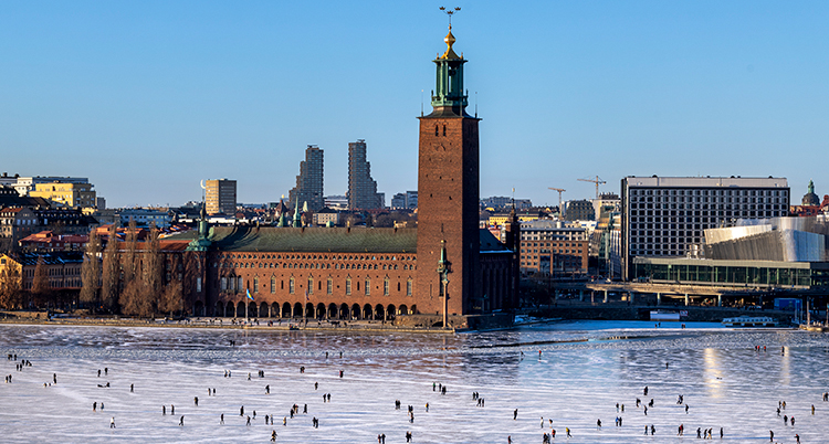 Isen är blank. Stadshuset syns och många människor på isen.