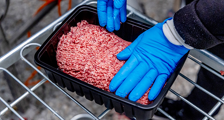 En person som lägger köttfärs i en låda.