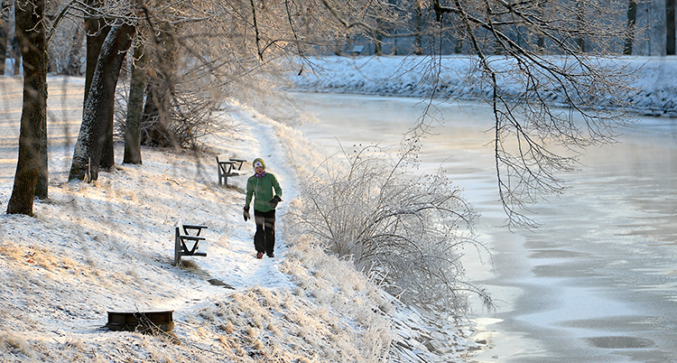 En kvinna promenerar. Det är frost och snö på träden och marken.