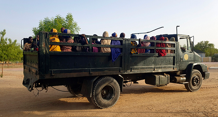 De sitter på flaket på en lastbil.