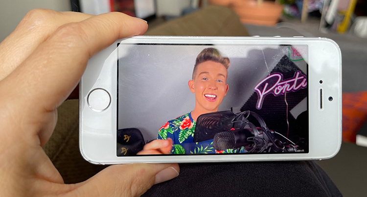 En hand håller i en mobil och tittar på en man.