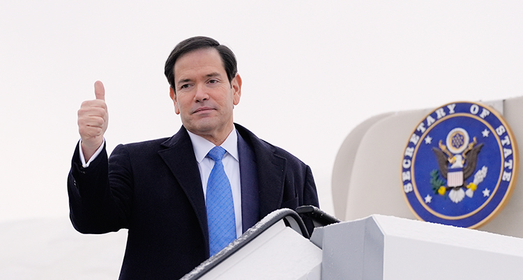 Han är på väg in i ett flygplan. Han vänder sig mot fotograferna och gör tummen upp.