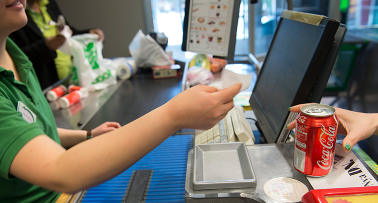 En person tar betalt i kassan i en butik.