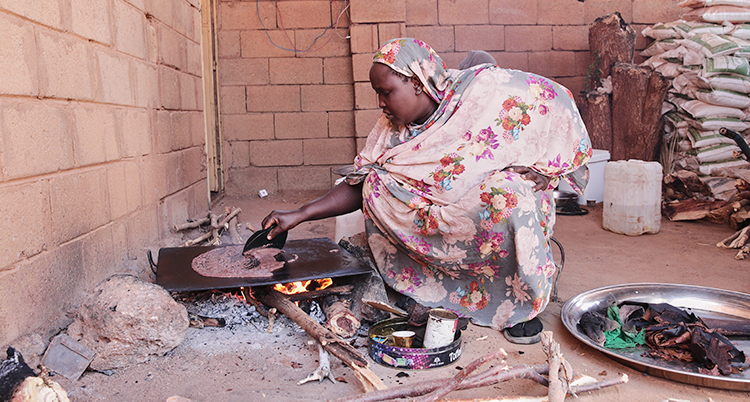 Hon sitter på huk och steker något som sedan ska användas i en dryck.