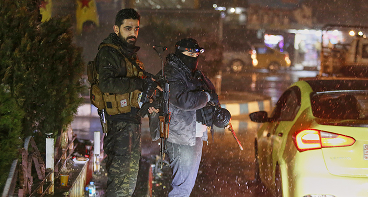 Det är mörkt ute. Två män står med vapen i en stad.