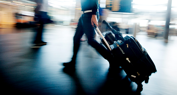 En person går och drar på en rullväska.