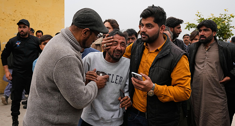 Två personer kramar om honom.