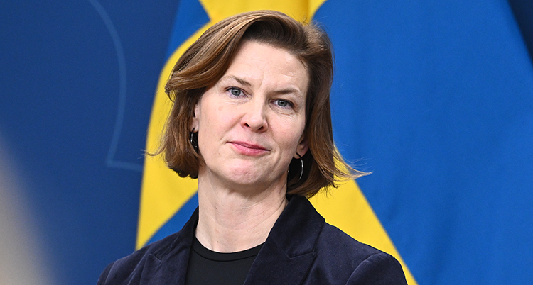 Hon står framför Sveriges flagga.