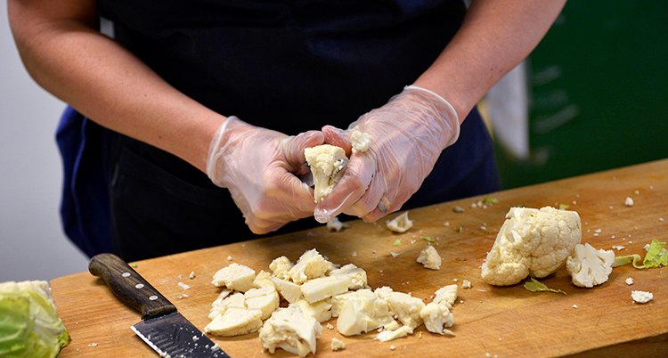 En person hackar blomkål.