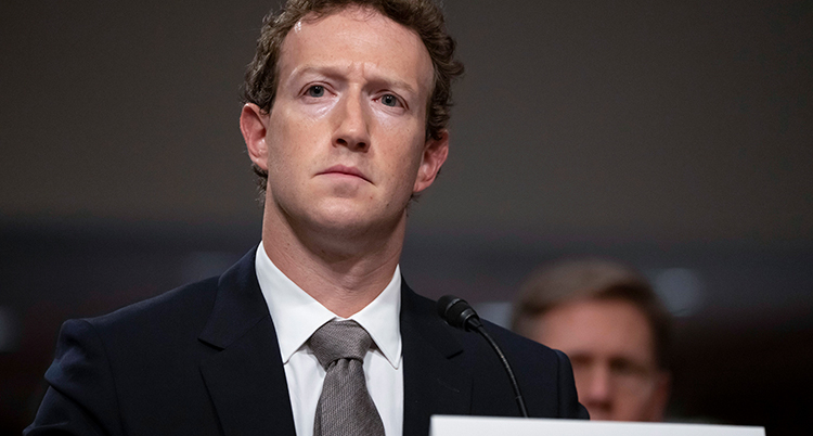 Han ser allvarlig ut. Han sitter bakom en mikrofon.