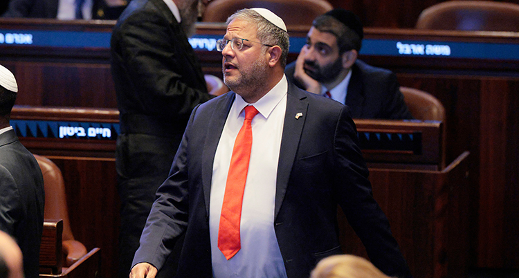 Han har kostym och slips. På huvudet har han en kippa. Han är Israels riksdag.