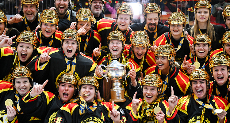 Spelarna är samlade med guldhjälmar på huvudet. De ler och skrattar och tittar in i kameran.