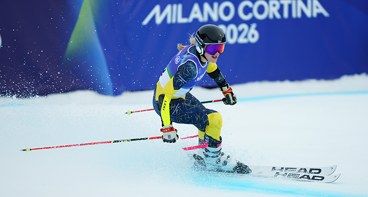 Hon åker på skidor och håller i stavar.