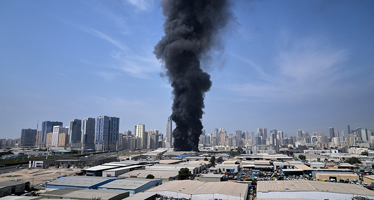 Svart rök från en explosion syns på himlen. Många höga hus syns nära.