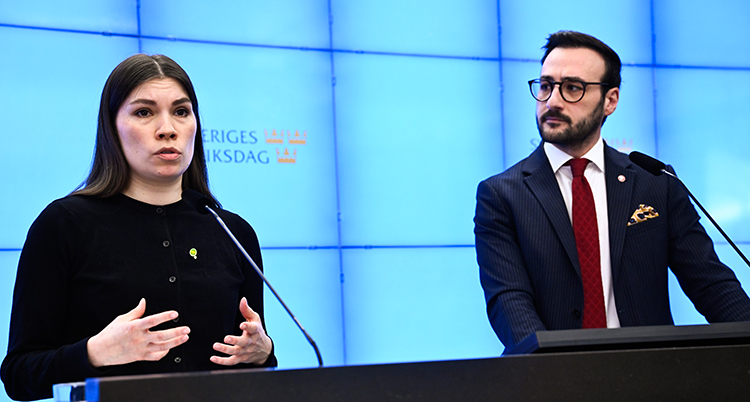 De står bredvid varandra och pratar in i mikrofoner.