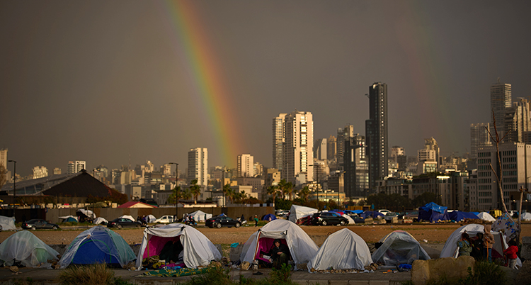Människor i flera tält en bit bort syns en stad.