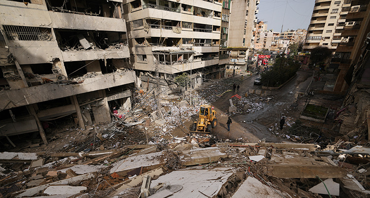 En traktor kör bort delar av det trasiga huset.