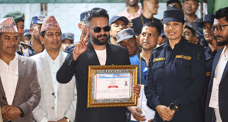 Han står framför massa folk. Han håller ett diplom och lyfter ena handen till en segergest. Han har solglasögon.