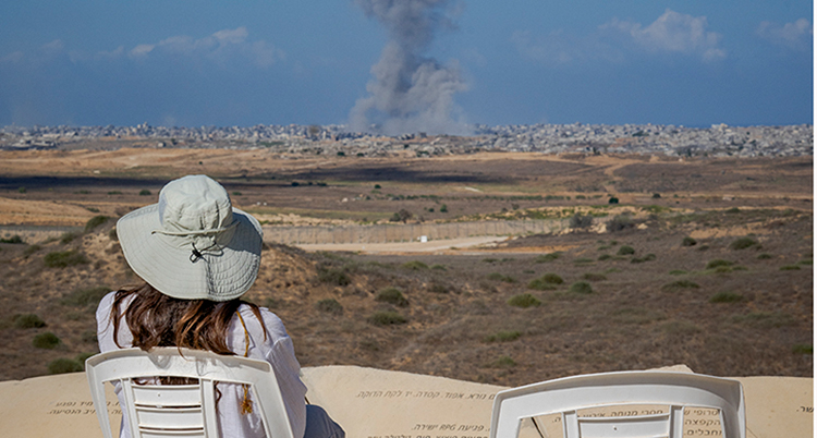 En kvinna i hatt tittar mot en stad och rök.