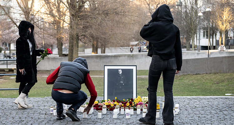 Några personer står framför ett foto av Einar, blommor och ljus.