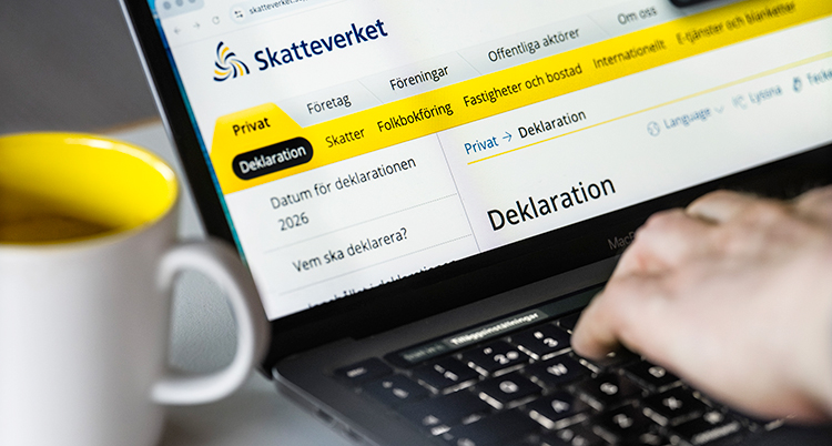 Närbild på en hand som skriver på tangentbordet till en dator. På datorn syns Skatteverkets hemsida.