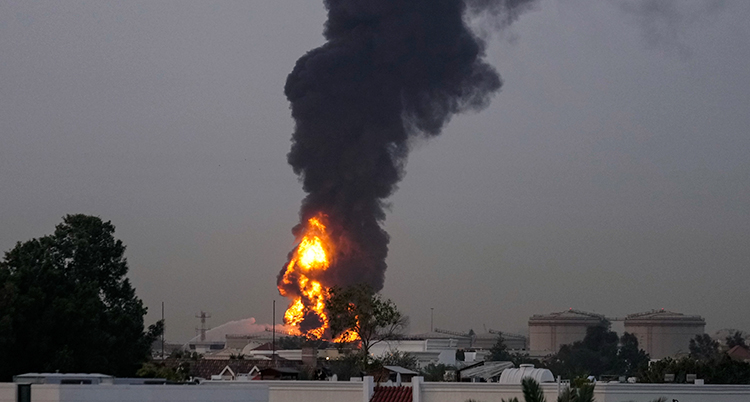 En stad. En bit bort är det en stor brand. Det kommer rök.