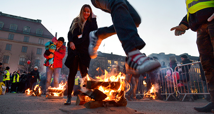 Kungsträdgården i Stockholm. Folk hoppar över små eldar som brinner på marken.