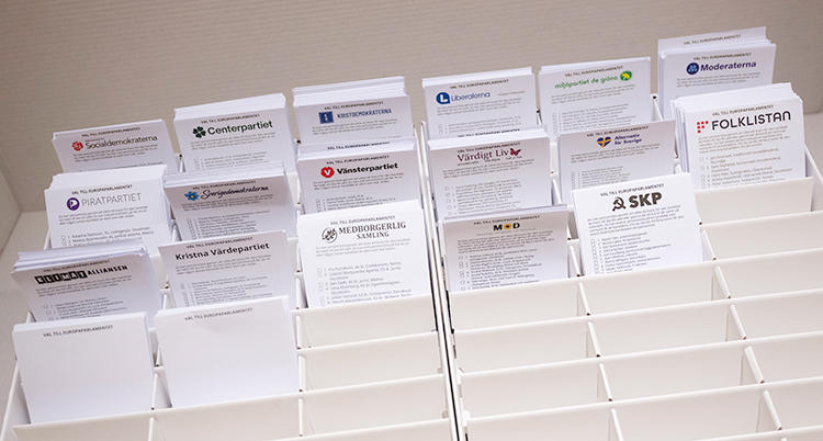 En låda med olika fack. Där står valsedlar för de olika partierna.