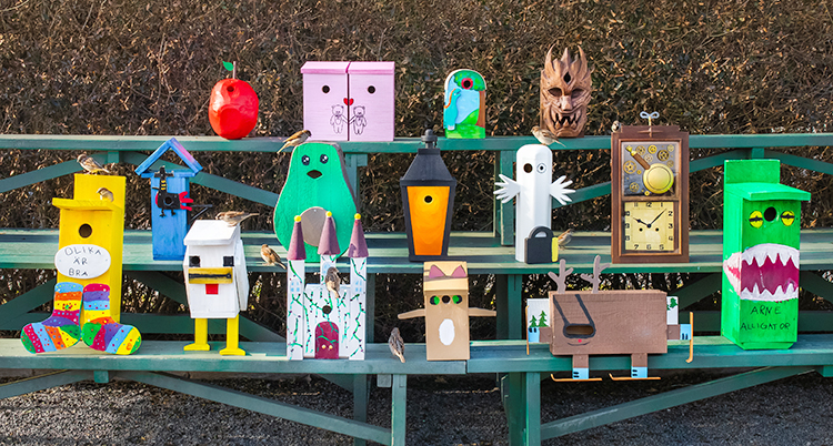 Femton olika fågelholkar. De har olika färger och former.