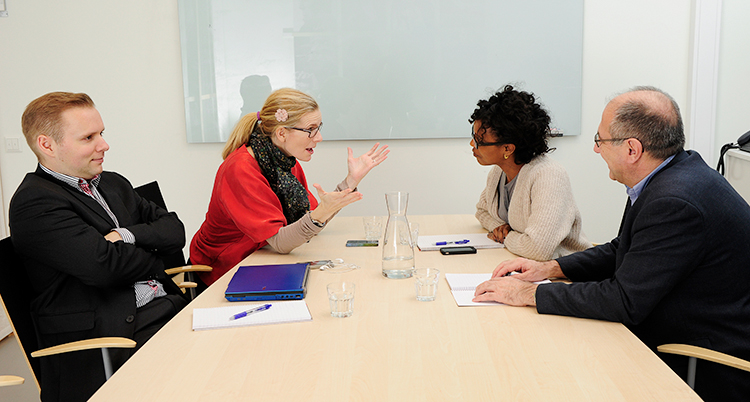 Fyra personer sitter vid ett bord och pratar med varandra.