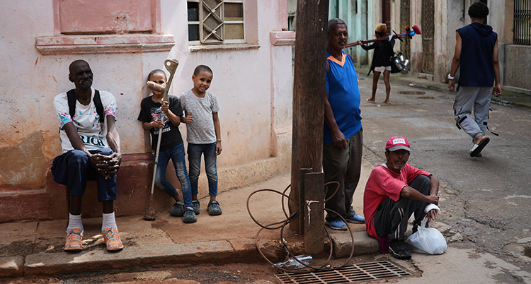 Människor sitter och står på en trottoar.
