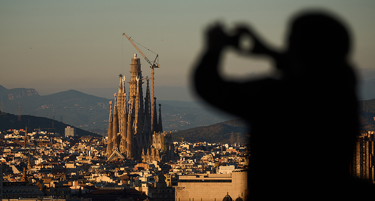 En siluett av en person syns i förgrunden. Bakom syns den höga kyrkan i staden.