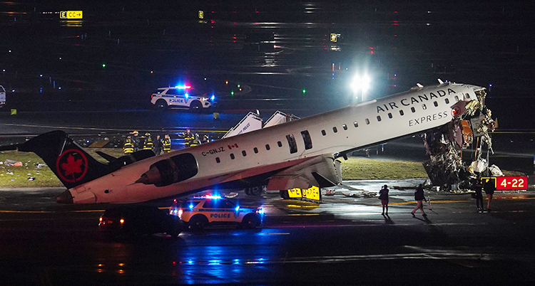 Ett flygplan har krockat. Nosen är trasig. Det hänger massa skräp och bråte från nosen. Flygplanet står på marken.