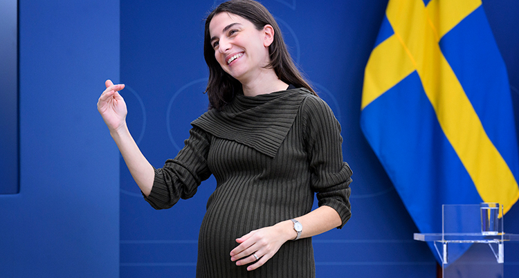 Hon står upp. Hennes mage är stor. Hon är gravid.