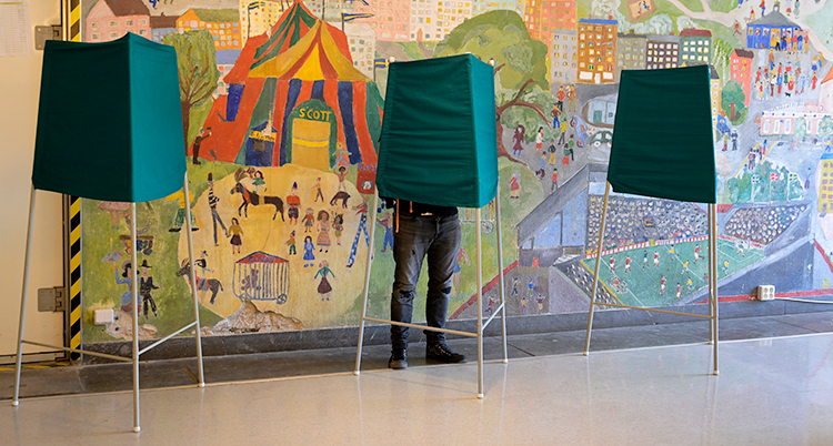 Ett rum i en skola. Där står tre stycken gröna skärmar. Bakom en av dem står en person.