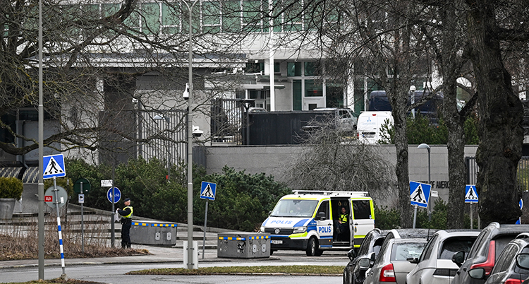 En polisbuss står utanför ett kontor.