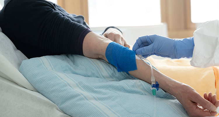 På ett sjukhus. En patient som får hjälp av en sjuksköterska.