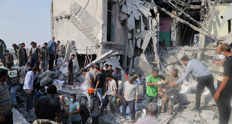 Många män står i ett stort hus som rasat.