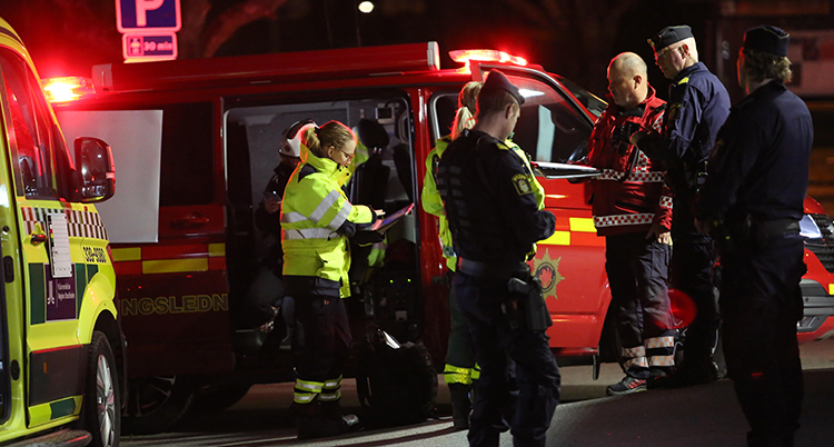 Flera personer står runt en ambulans.