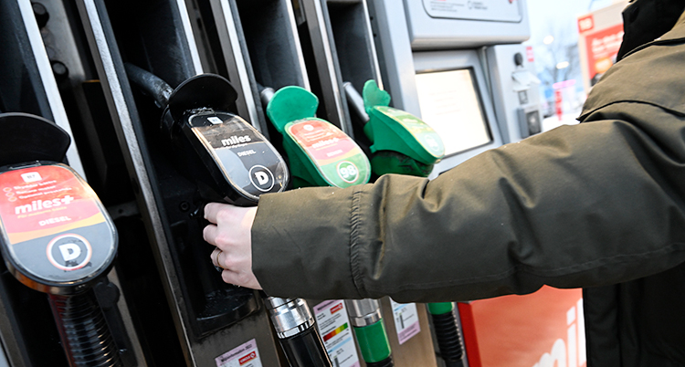 En person står vid en pump på en bensinmack.