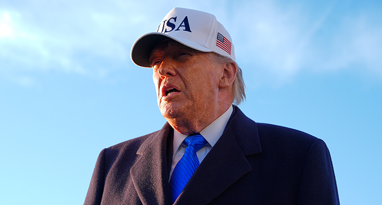 Han har en vit keps med texten USA på. Han pratar och ser allvarlig ut.