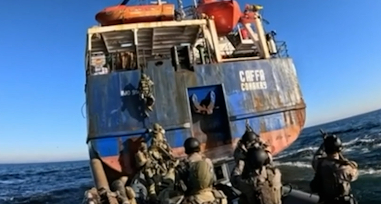 Militärer kommer med en liten båt. De klättrar upp på den stora båten.