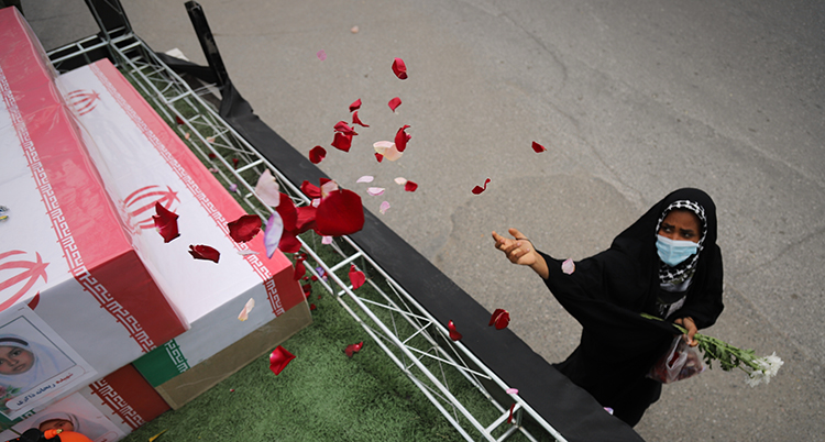 Hon står nedan för en lastbil. Hon kastar blommorna upp på graven som är på lastbilen.