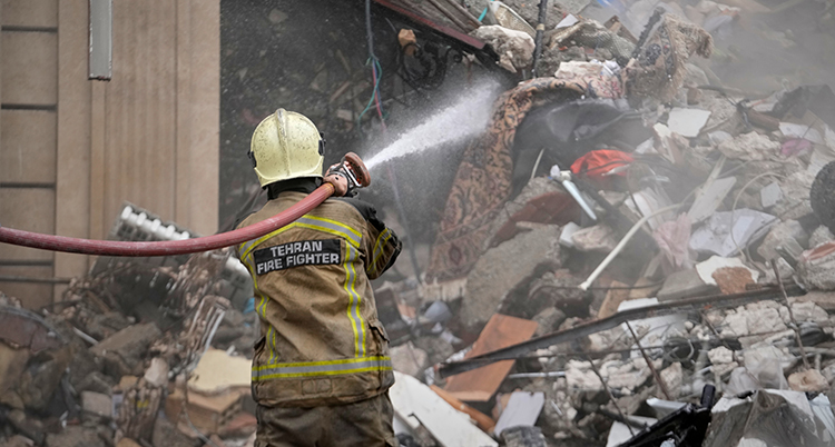 Han sprutar vatten mot det förstörda huset.