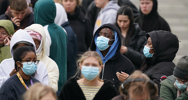 De står i kö. Många har skydd för munnen.