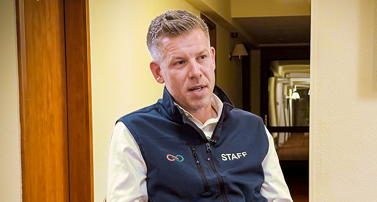 Han sitter på en stol och pratar.