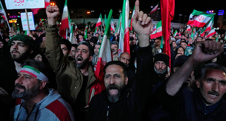 Folk ropar och viftar med Irans flaggor.