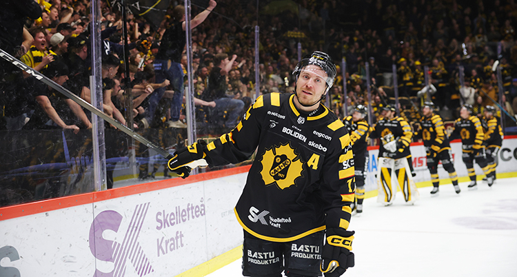 Han åker på isen. Han sträcker handen mot publiken.