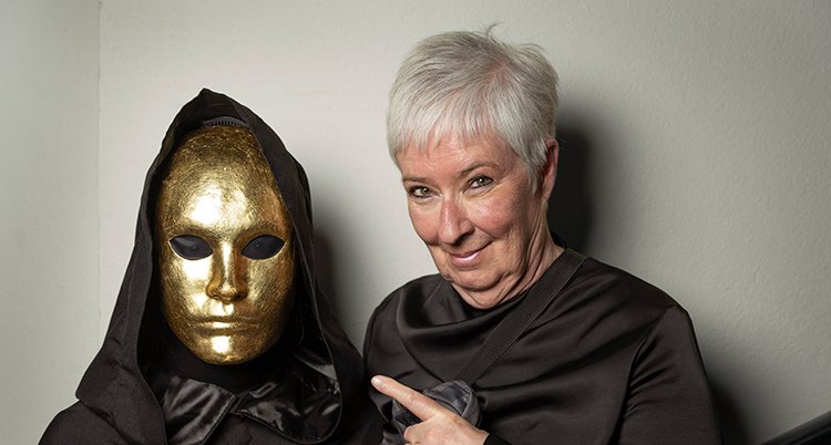 Hon pekar på ett ansikte som har en mask av guld.